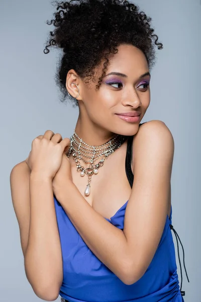 Smiling african american model in bright dress posing isolated on grey — Stock Photo