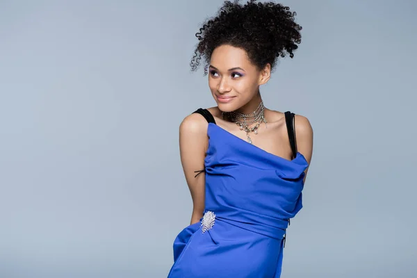 Smiling african american model in slip dress looking away while posing isolated on grey — Stock Photo