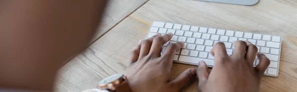 Vista recortada del hombre afroamericano escribiendo en el teclado de la computadora, bandera - foto de stock