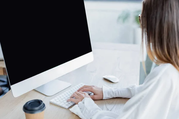 Junge Geschäftsfrau tippt auf Tastatur in der Nähe des Computermonitors — Stockfoto