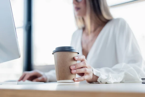 Cropped view of young woman holding paper cup in office — Stock Photo