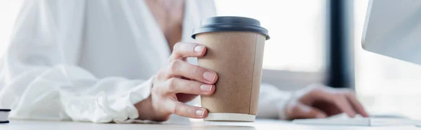 Vista ritagliata di giovane donna in possesso di tazza di carta in ufficio, banner — Foto stock