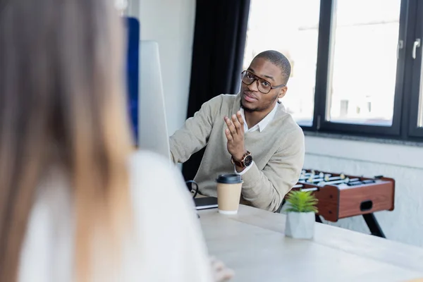 Afrikanisch-amerikanischer Mann mit Brille schaut verschwommene Frau im Büro an — Stockfoto