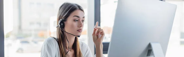 Empresária em fone de ouvido olhando para monitor de computador ao apontar com o dedo, banner — Fotografia de Stock