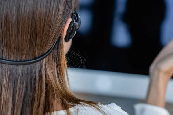 Back view of businesswoman in headset near blurred monitor — Stock Photo