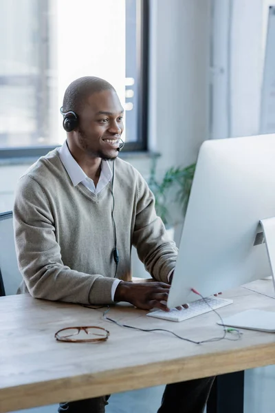 Gai opérateur afro-américain dans casque regardant moniteur d'ordinateur — Photo de stock