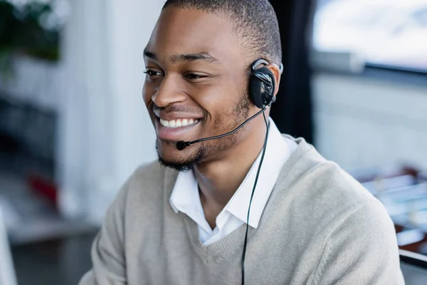 Joyful african american operator in headset smiling in office — Stock Photo