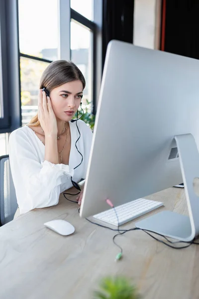 Pensive operator in headset using computer in office — Stock Photo