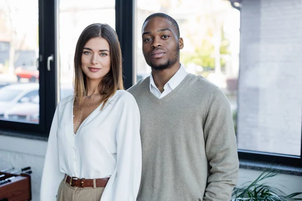 Homem de negócios interracial e mulher de negócios olhando para a câmera — Fotografia de Stock