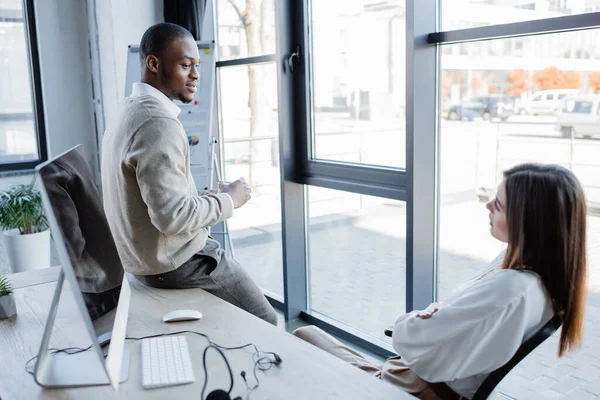 Afrikanischer amerikanischer Geschäftsmann schaut hübsche Kollegin im Büro an — Stockfoto