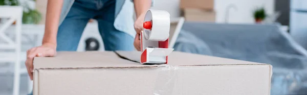 Cropped view of woman holding adjusting tape near carton box, banner — Stock Photo