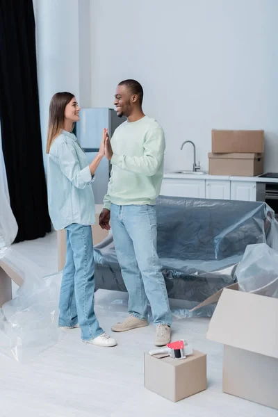 Cheerful interracial couple giving high five in new apartment — Stock Photo