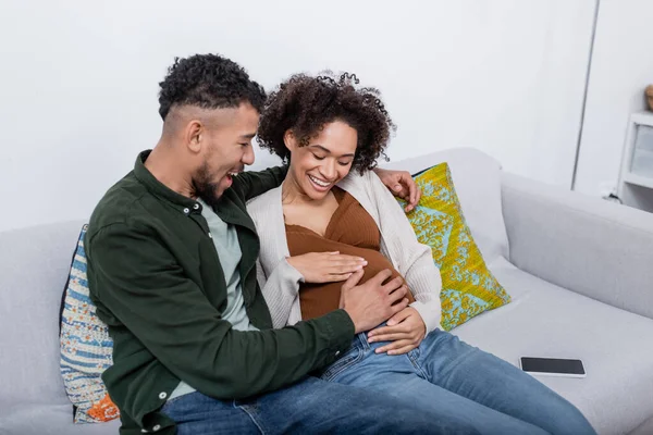 Animado afro-americano homem tocando barriga de mulher grávida — Fotografia de Stock