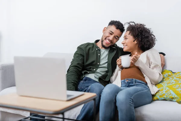 Feliz africano americano marido y embarazada esposa viendo película en el ordenador portátil — Stock Photo