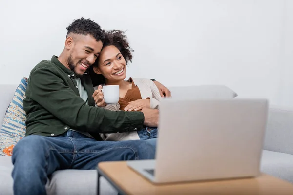 Allegro africano americano uomo abbracciare moglie incinta vicino computer portatile offuscata — Foto stock