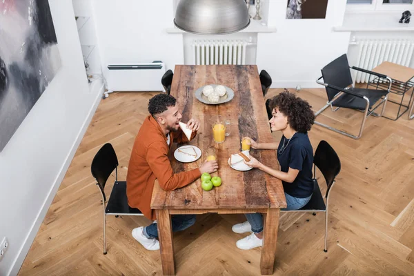 Vista ad alto angolo di felice donna afro-americana che pranza con fidanzato allegro — Foto stock