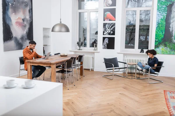 Freelance afro-americano che lavora da casa vicino alla fidanzata riccia usando tablet digitale — Foto stock