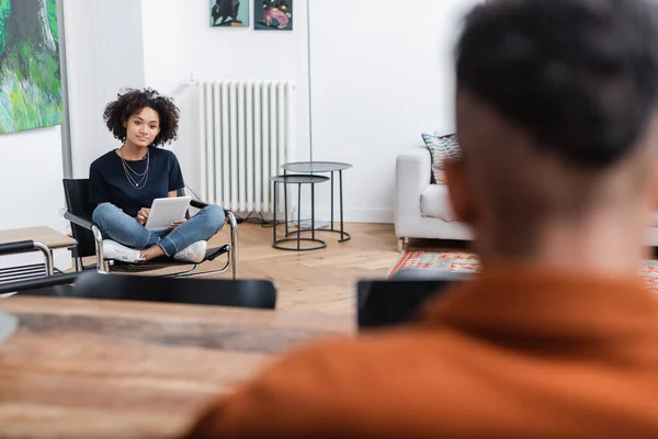 Joyeuse femme afro-américaine tenant tablette numérique près de copain flou — Photo de stock