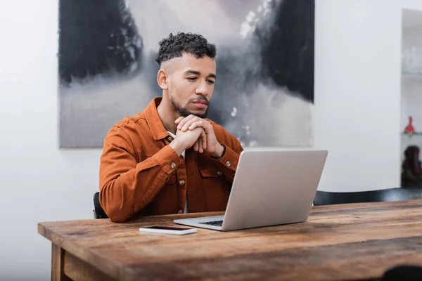 Afrikanisch-amerikanischer Freiberufler schaut von zu Hause aus auf Laptop — Stockfoto