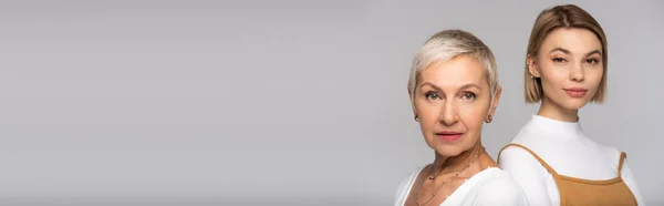 Middle aged mother and young daughter looking at camera isolated on grey, banner — Stock Photo