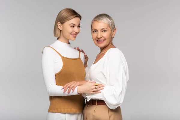 Glückliche Mutter mittleren Alters und fröhliche kleine Tochter umarmen isoliert auf grau — Stockfoto