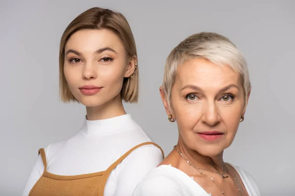 Young woman near blurred middle aged mother looking at camera isolated on grey — Stock Photo