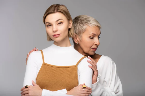 Mère d'âge moyen câlin jeune fille avec les bras croisés isolé sur gris — Photo de stock