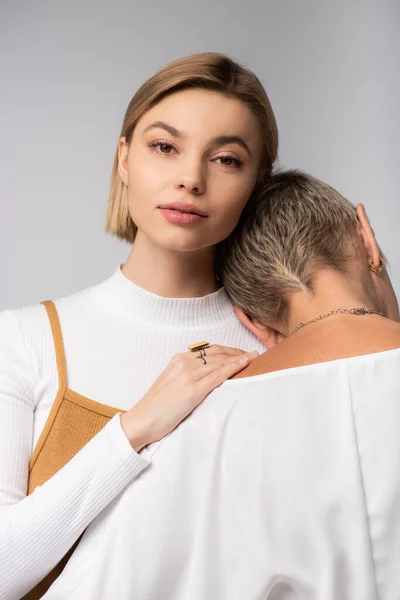 Junge Frau umarmt Mutter mittleren Alters isoliert auf grau — Stockfoto