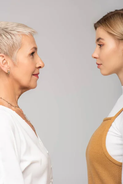 Side view of young woman and mature mother looking at each other isolated on grey — Stock Photo