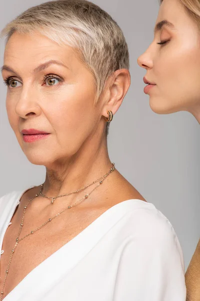 Young woman near mature mother isolated on grey — Stock Photo