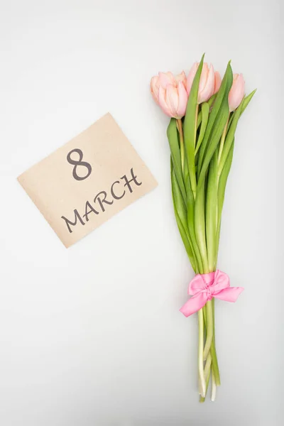 Vista dall'alto di tulipani rosa con nastro vicino carta artigianale con 8 lettere marcianti isolate su bianco — Foto stock