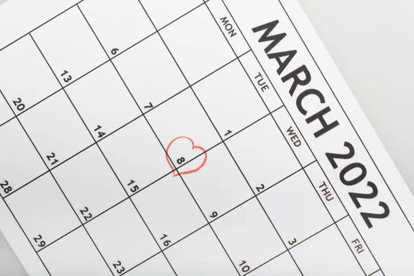 Top view of march 2022 calendar with drawn heart around 8 march date isolated on grey — Stock Photo