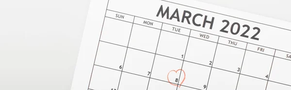 Top view of march 2022 calendar with drawn heart around 8 march date isolated on white, banner — Stock Photo