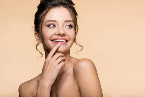 Sorrindo mulher morena com ombros nus olhando para longe isolado no bege — Fotografia de Stock