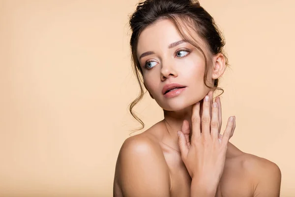 Hübsche brünette Frau mit nackten Schultern, die auf beige isoliert wegschaut — Stockfoto