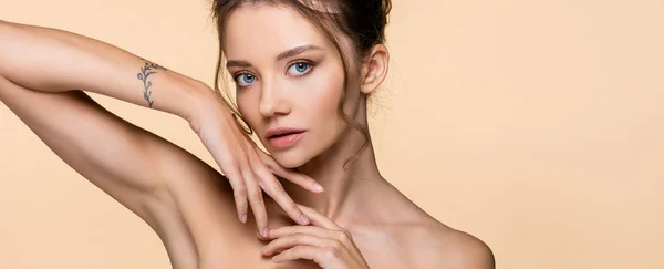 Young woman with naked shoulders looking at camera isolated on beige, banner — Stock Photo