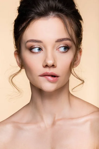 Young woman with naked shoulders biting lip isolated on beige — Stock Photo