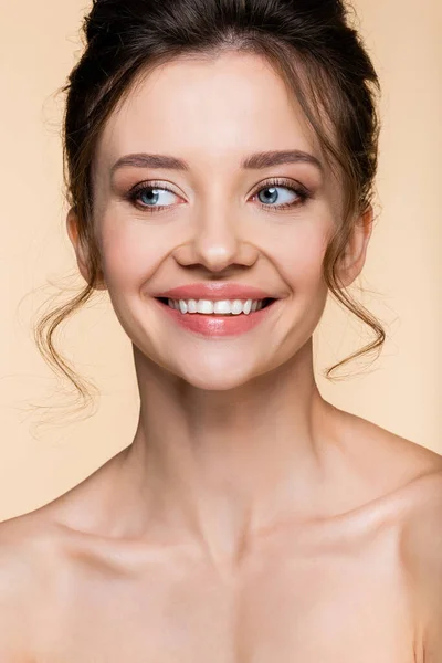 Retrato de una mujer sonriente mirando hacia otro lado aislada en beige - foto de stock