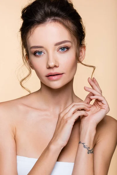 Young model in top looking at camera isolated on beige — Stock Photo