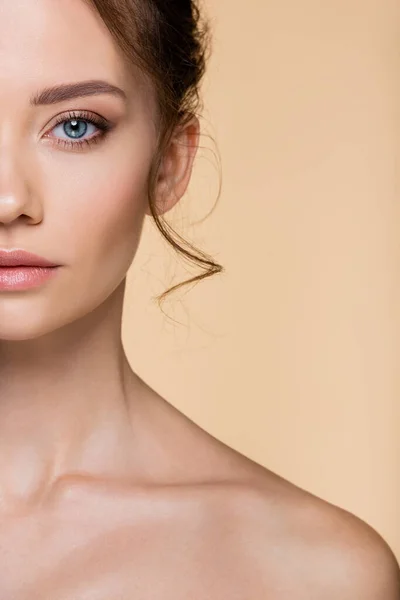 Cropped view of young woman with naked shoulder looking at camera isolated on beige — Stock Photo