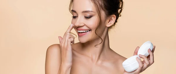 Mulher positiva aplicando creme cosmético no nariz isolado em bege, banner — Fotografia de Stock