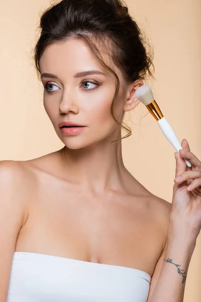 Bonito modelo en cepillo cosmético de fijación superior aislado en beige - foto de stock