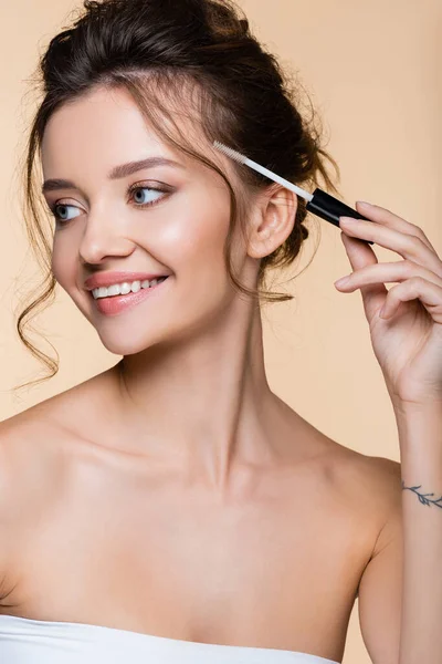 Positive model holding cosmetic brush of eyebrow gel isolated on beige — Stock Photo
