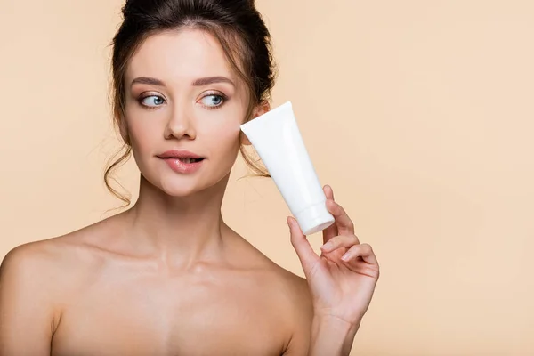 Modello pensieroso con spalle nude con lozione cosmetica isolata su beige — Foto stock