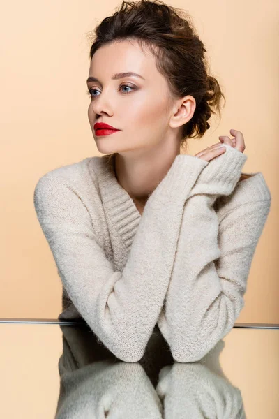 Mujer joven posando cerca de espejo aislado en beige - foto de stock