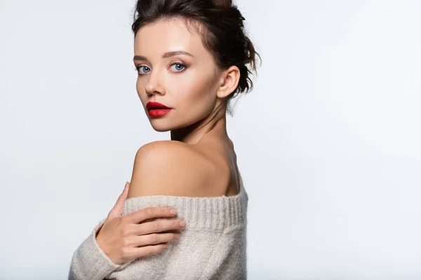 Stylish young woman touching sweater and looking at camera isolated on white — Stock Photo