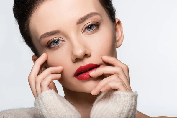 Porträt eines jungen Models mit roten Lippen, die das Gesicht berühren und die Kamera isoliert auf Weiß betrachten — Stockfoto