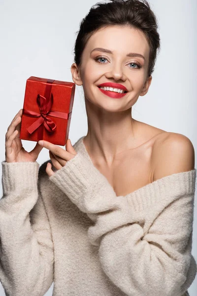Positive stylish model holding red present isolated on white — Stock Photo