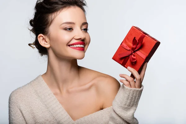 Elegante modello in maglione con spalla nuda tenuta presente e sorridente isolato su bianco — Foto stock