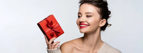 Pretty woman with red lips looking at gift box isolated on white, banner — Stock Photo